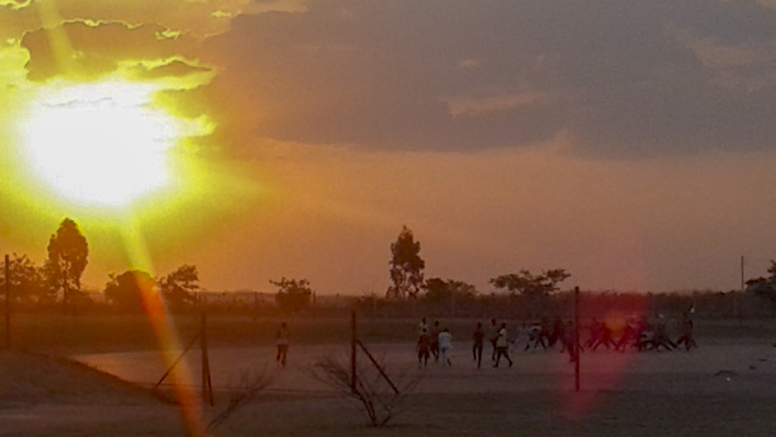 People playing football in Zambia at sunset