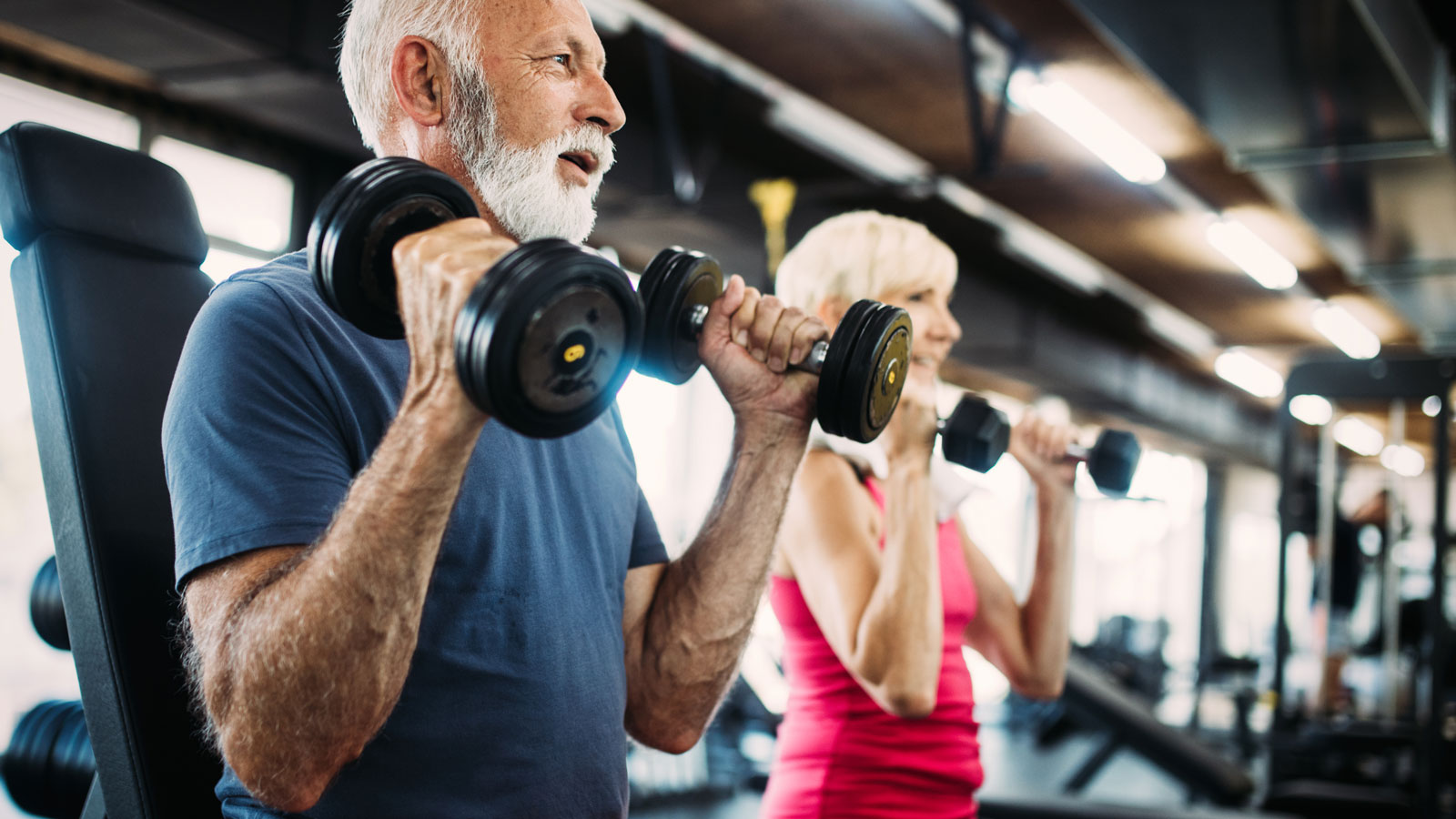 Elderly couple train bisceps with dumbbells