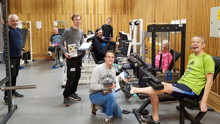 Gruppe eldre trener styrke på apparater i treningssal