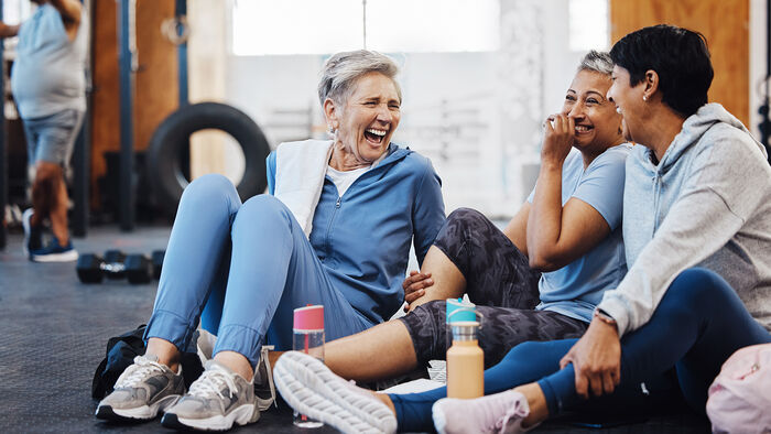 tre kvinner ler mens de tar en pause i trening 