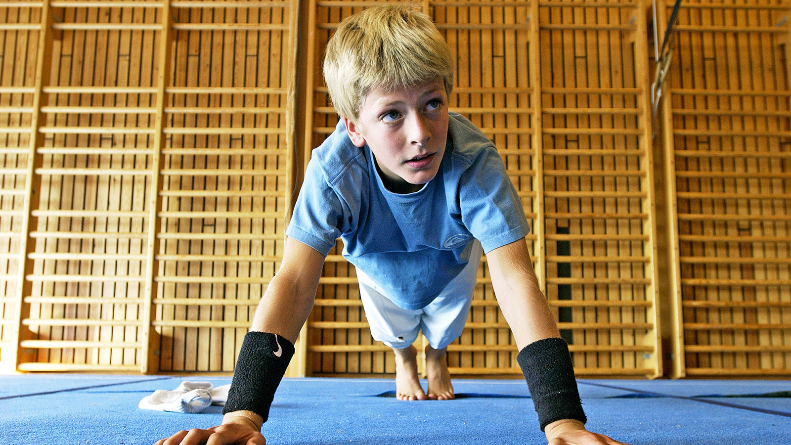 en gutt gjør armhevninger i en gymsal