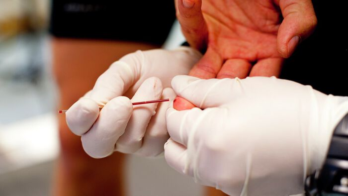 Labingeniør tar blodrprøve fra en fingeren av en utøver