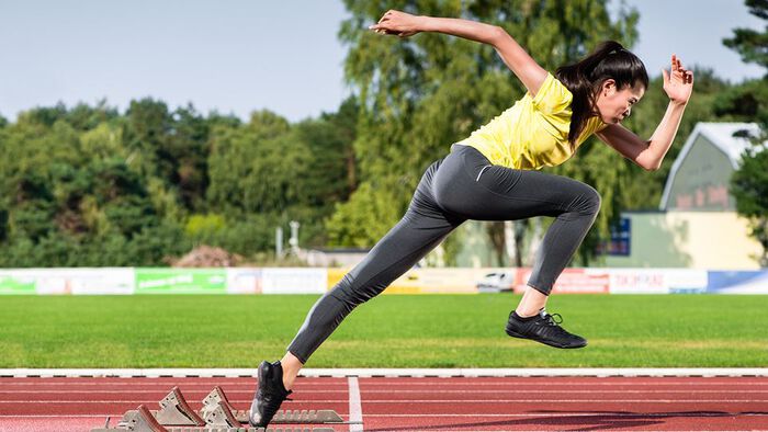 Kvinnelig utøver sprinter ut fra startblokker