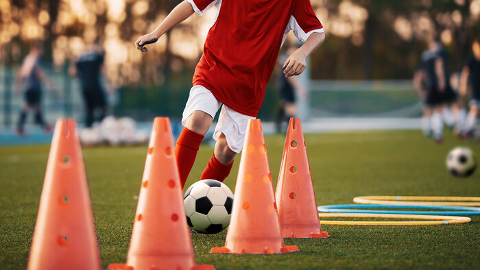 Gutt kjører fotball øvelser rundt kegler