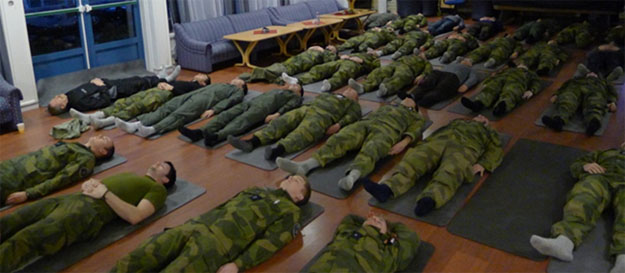 Soldater i uniform ligger på rygg i et rom.