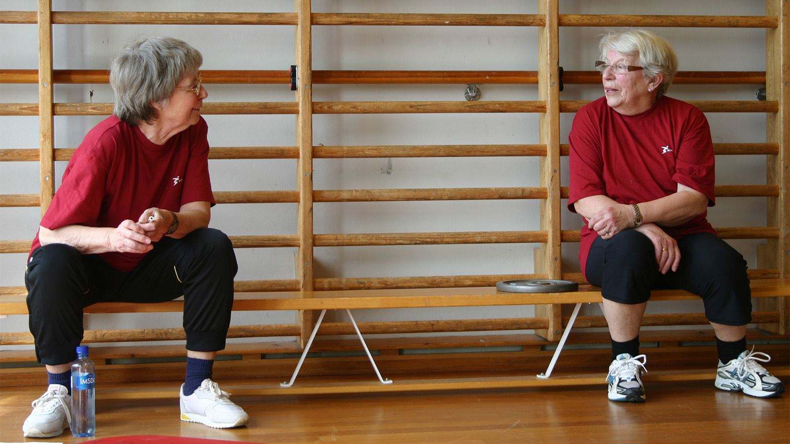 To seniorer som sitter i en gymsal