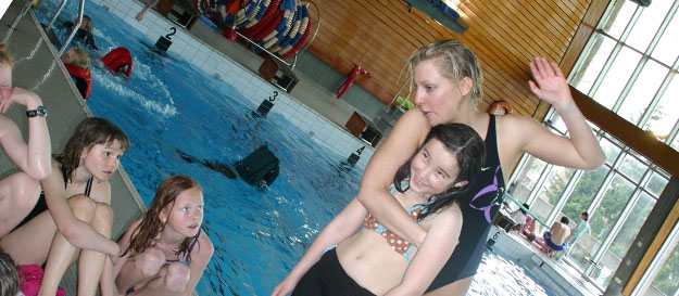Svømmeinstruktøren viser teknikk til klassen i svømmehallen