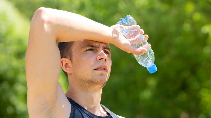 En mann tar en pause fra trening med en vannflaske i hånda