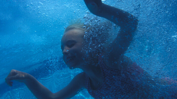 Bilde av et barn som svømmer under vann i et bassseng