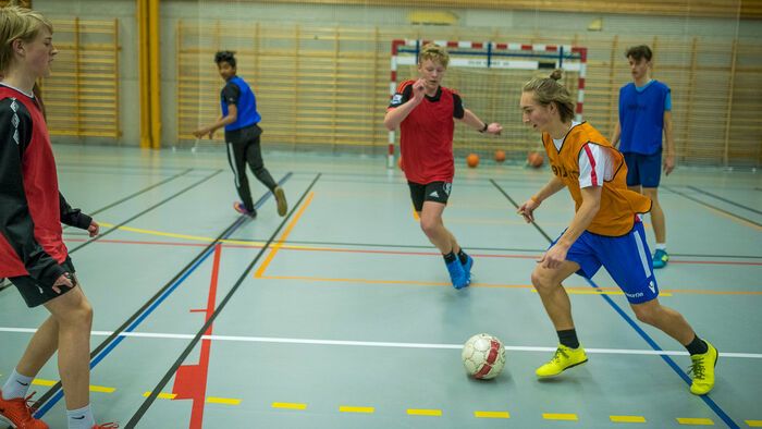 Youths playing football indoors