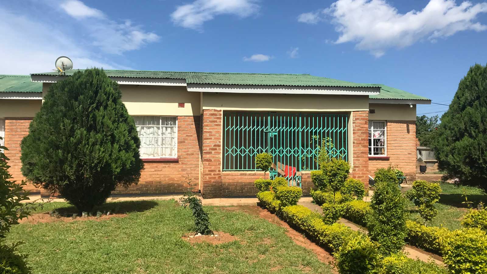 verthus i Malawi av murstein med et lav tak i et grønt landskap