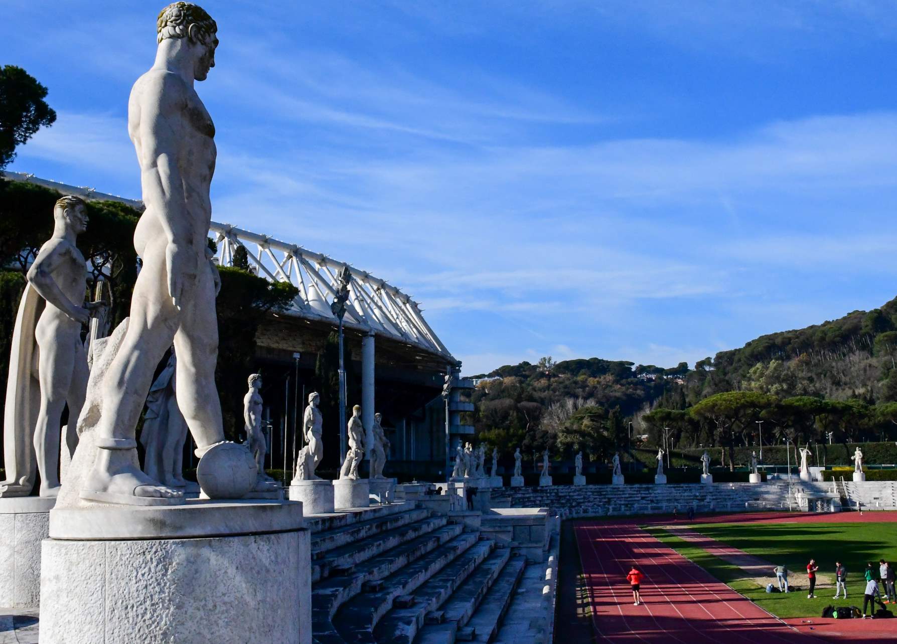Romerske statuer rundt friidrettsbanen, med fotballstadion i bakgrunnen.